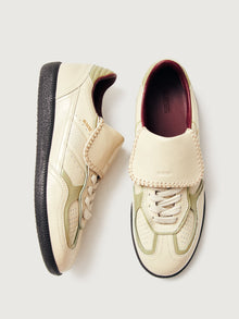 Creme colored low top lifestyle sneaker with black sole & gold/creme heel detailing. 