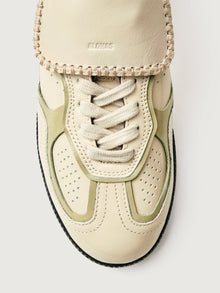 Creme colored low top lifestyle sneaker with black sole & gold/creme heel detailing. 