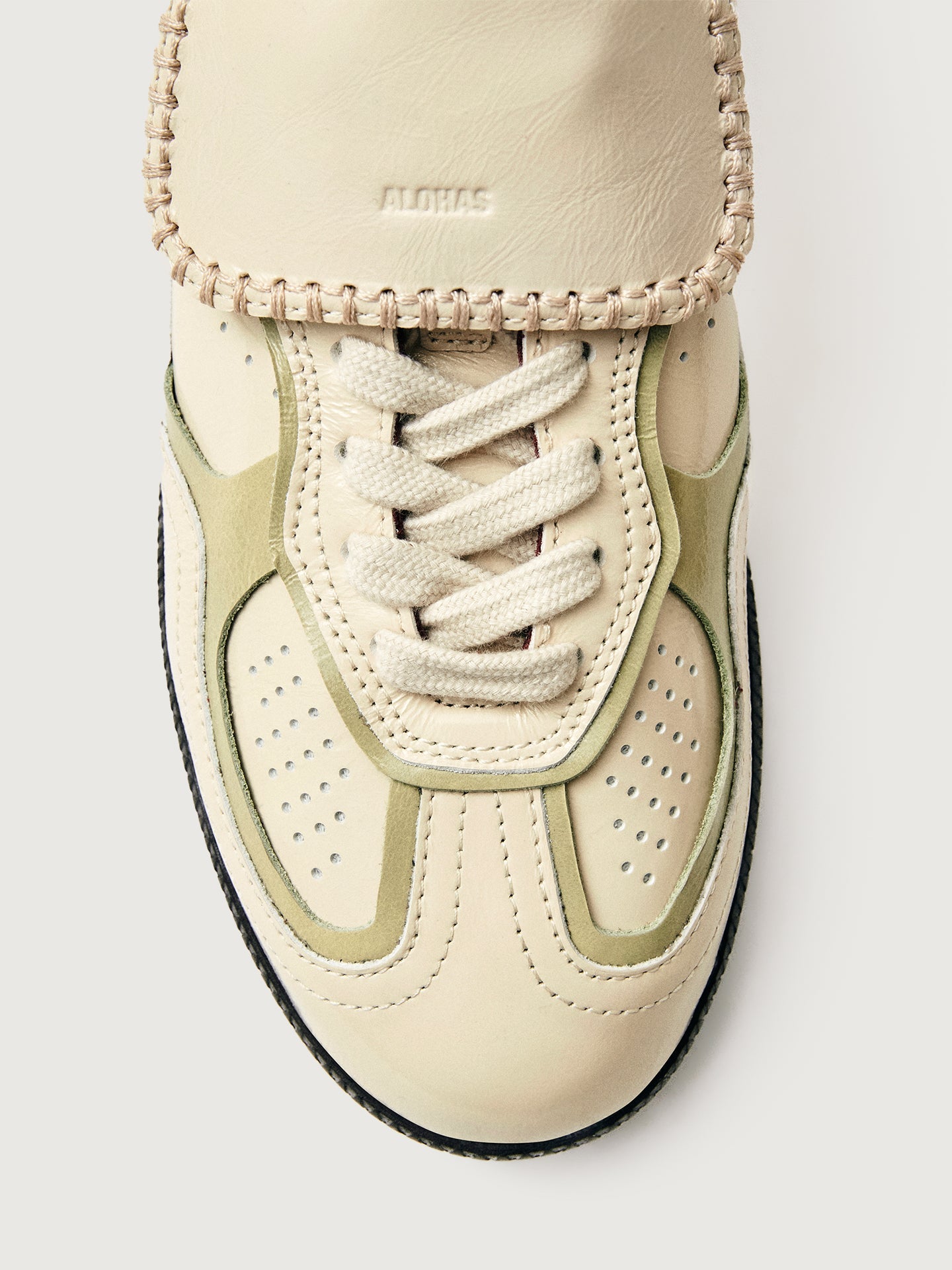 Creme colored low top lifestyle sneaker with black sole & gold/creme heel detailing. 
