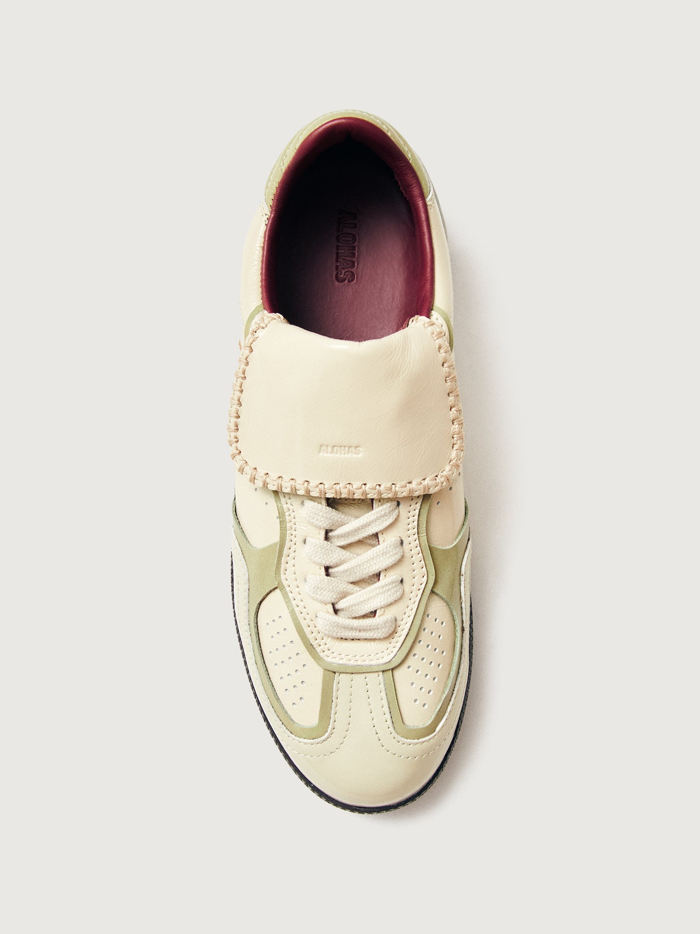 Creme colored low top lifestyle sneaker with black sole & gold/creme heel detailing. 