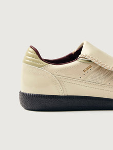 Creme colored low top lifestyle sneaker with black sole & gold/creme heel detailing. 