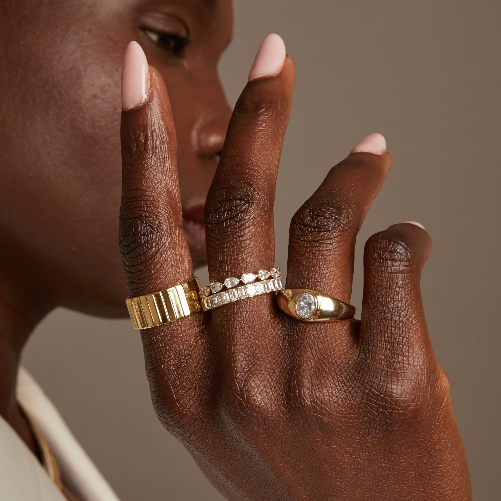 Model. Close up of woman wearing various ring on neutral background
