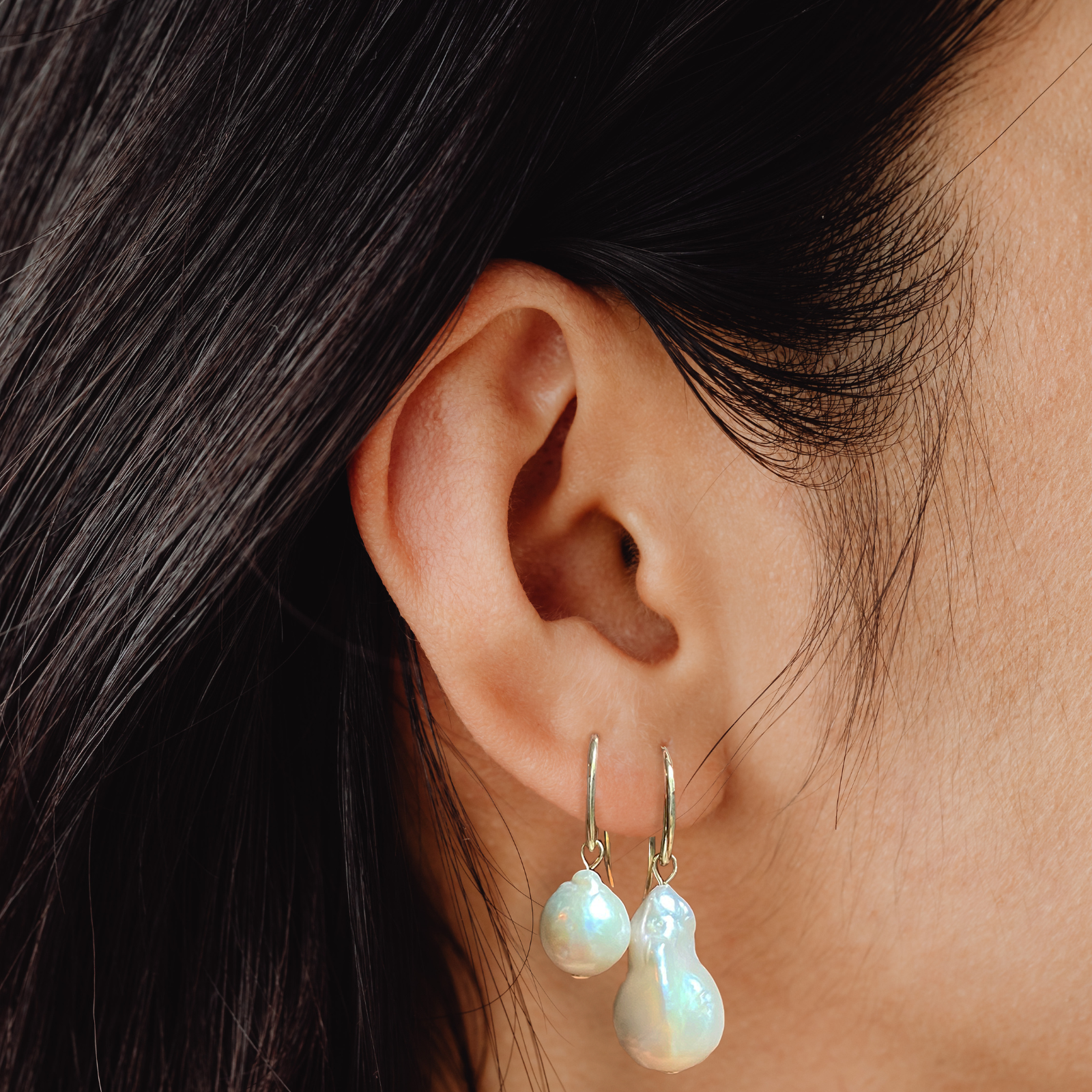 14k gold Mini Baroque Pearl Drop Earrings styled on a ear next to the large baroque pearl drop earring