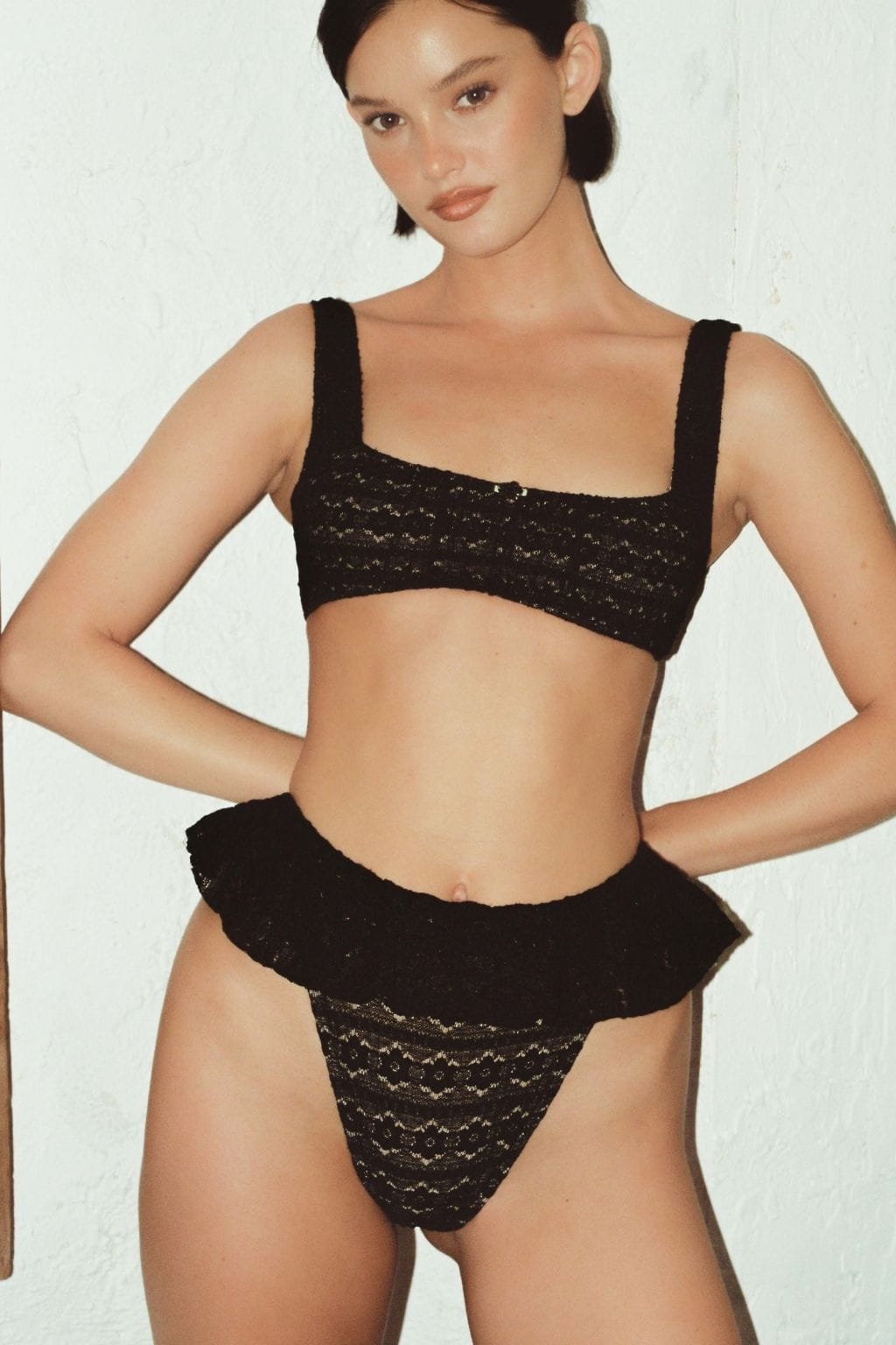 Black lace bikini bottom with ruffle waistband detail and daisy pattern.