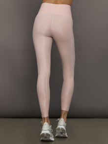 Model wears a pair of high rise baby pink sleek liquidy shine leggings. 