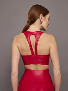 Model wears a bright red shiny, liquidlike sports bra with a v neck. 