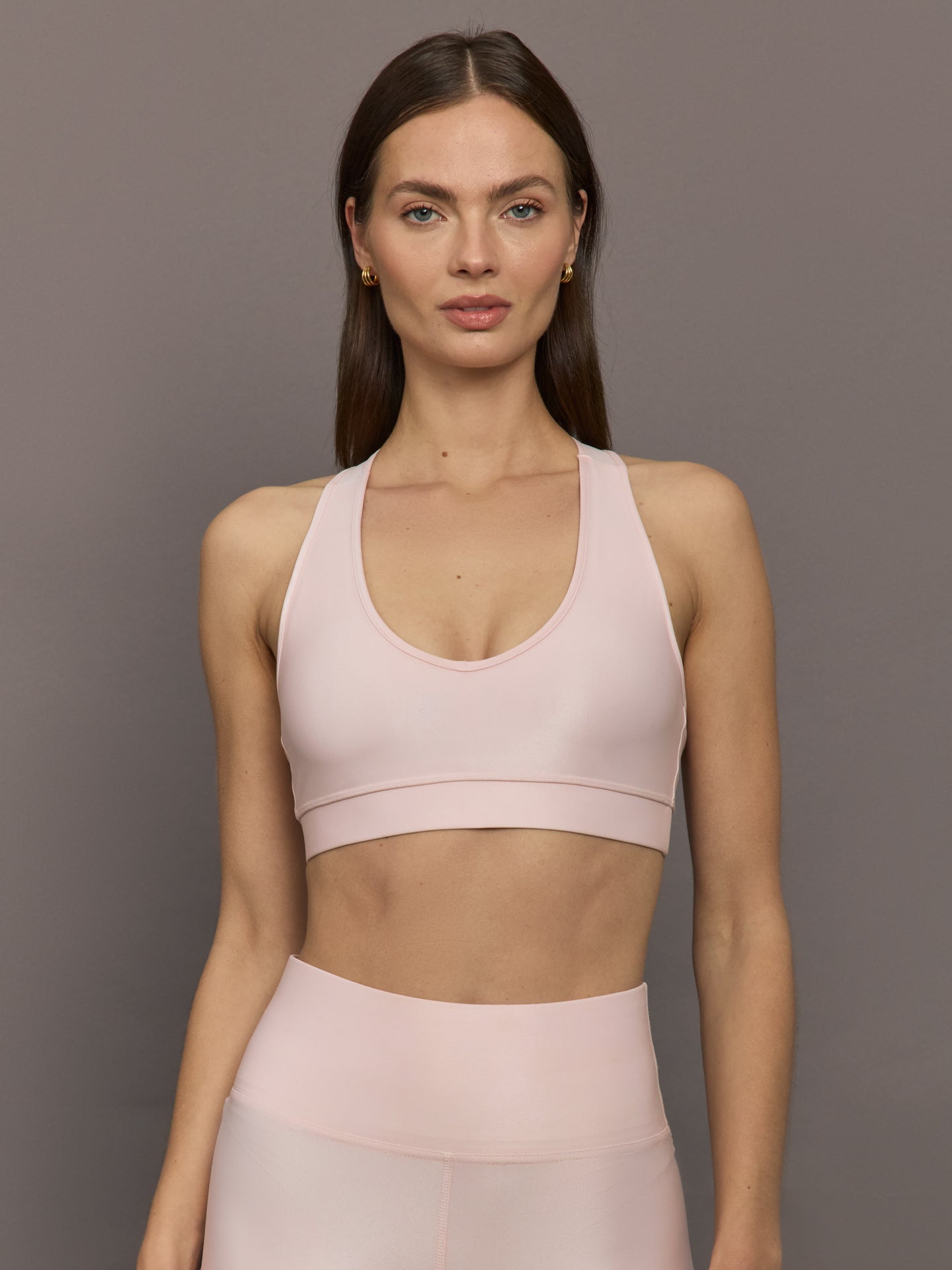 Model wears a v neck baby pink bra in a liquidy takara shine finish. 
