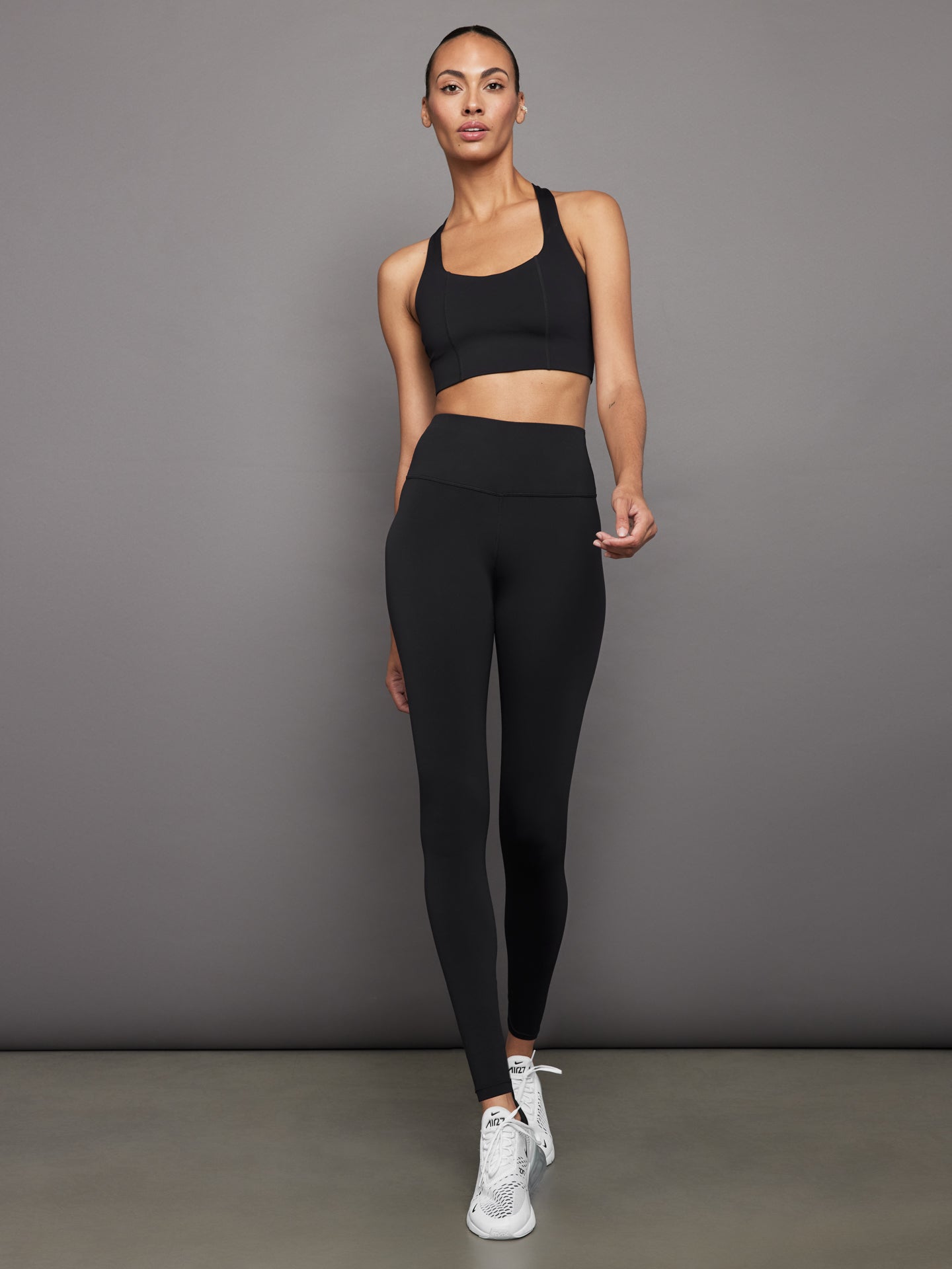 Full outfit view of model in black diamond compression T-back sports bra with matching leggings.