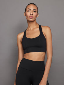 Model wearing black diamond compression T-back sports bra, front view.