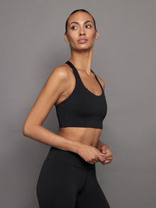 Side view of black compression T-back sports bra with scoop neckline.