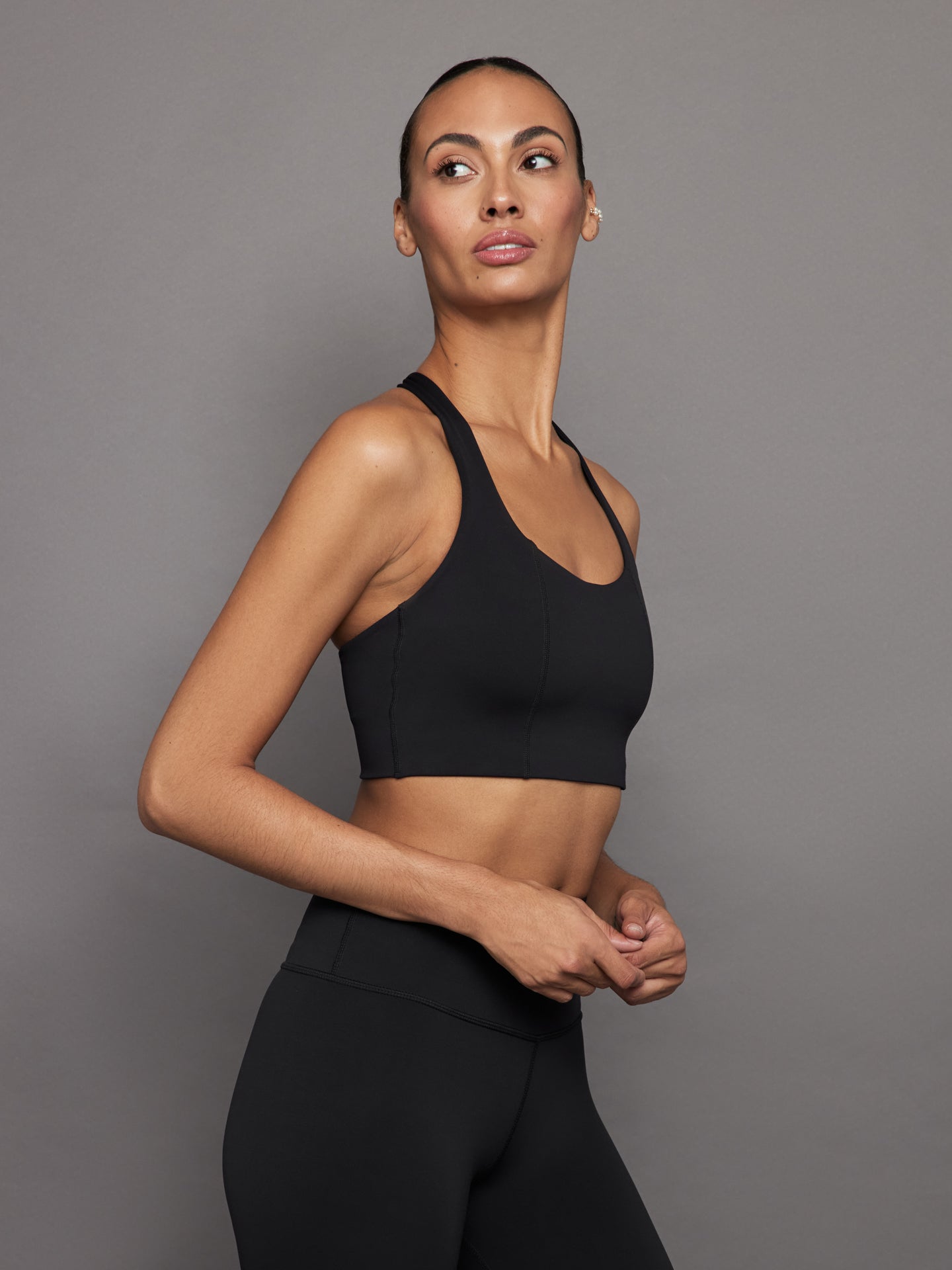 Side view of black compression T-back sports bra with scoop neckline.