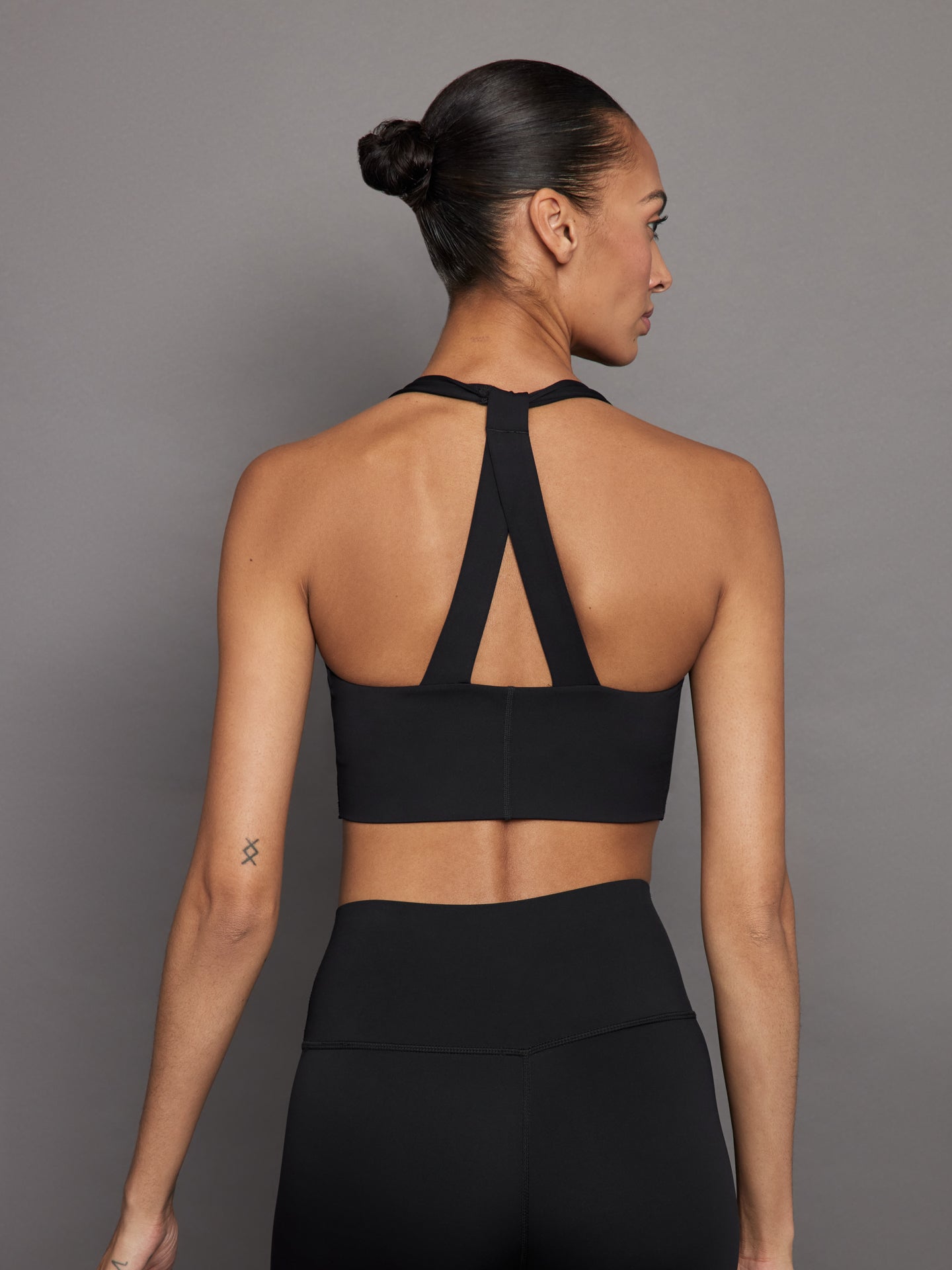 Back view of black T-back sports bra showing halter straps.