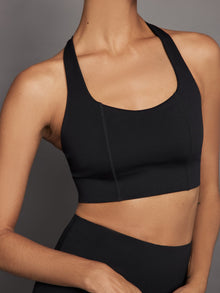 Close-up of black T-back bra showing seam and neckline detail.