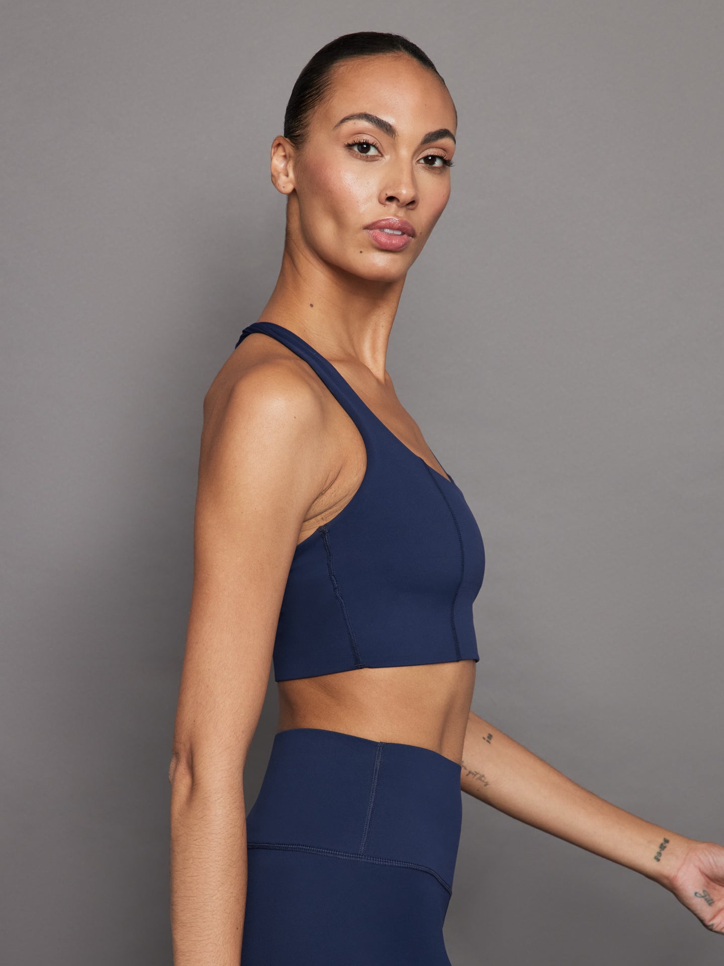 Side profile of model in navy compression T Back bra.