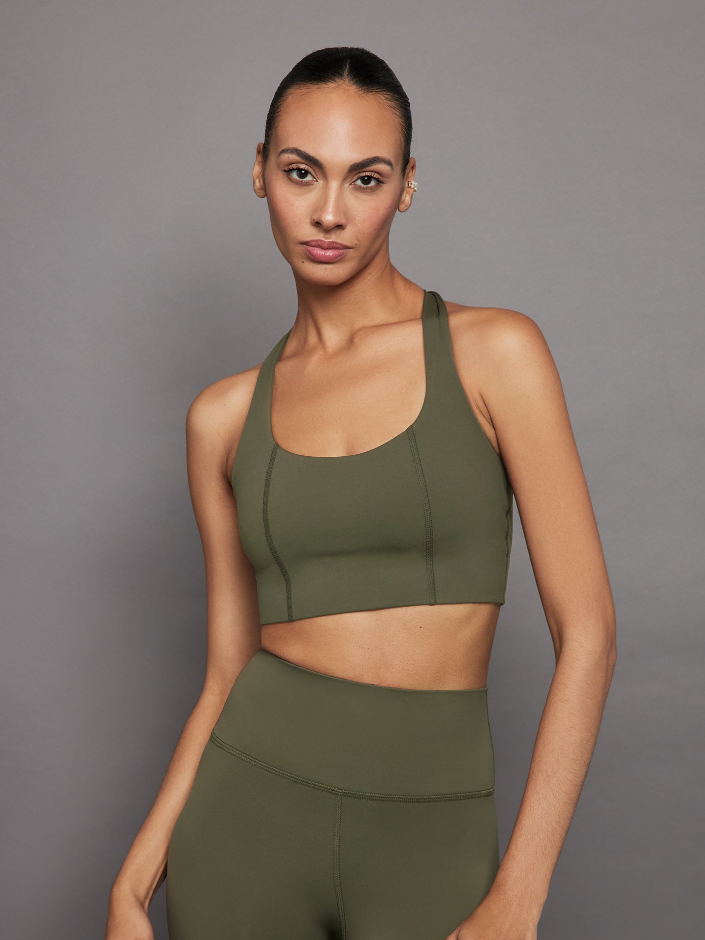 Model wearing olive Diamond Compression T Back Bra, front view.