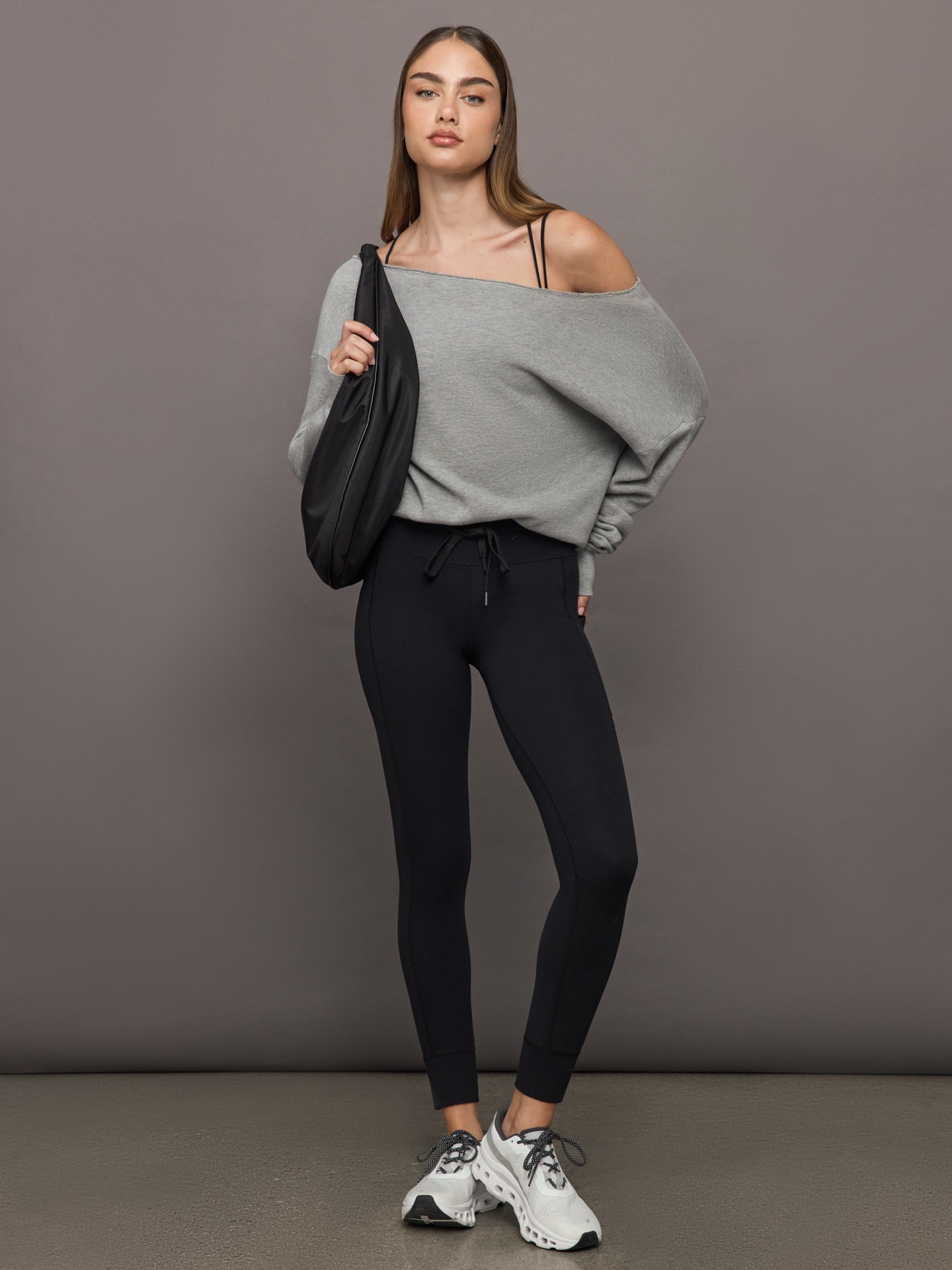 Model styled in Melt High Rise Sport Pocket Legging Black with gray oversized sweater and crossbody bag.
