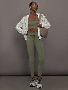 Model styled in Melt High Rise Sport Pocket Legging Moss with matching bandeau and white knit cardigan, full body view.