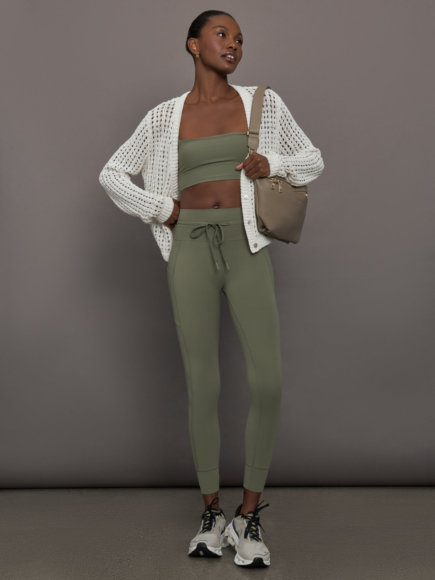 Model styled in Melt High Rise Sport Pocket Legging Moss with matching bandeau and white knit cardigan, full body view.