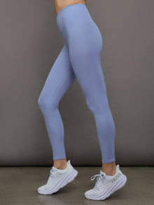 Model wears a pair of high waisted periwinkle colored ribbed leggings. 