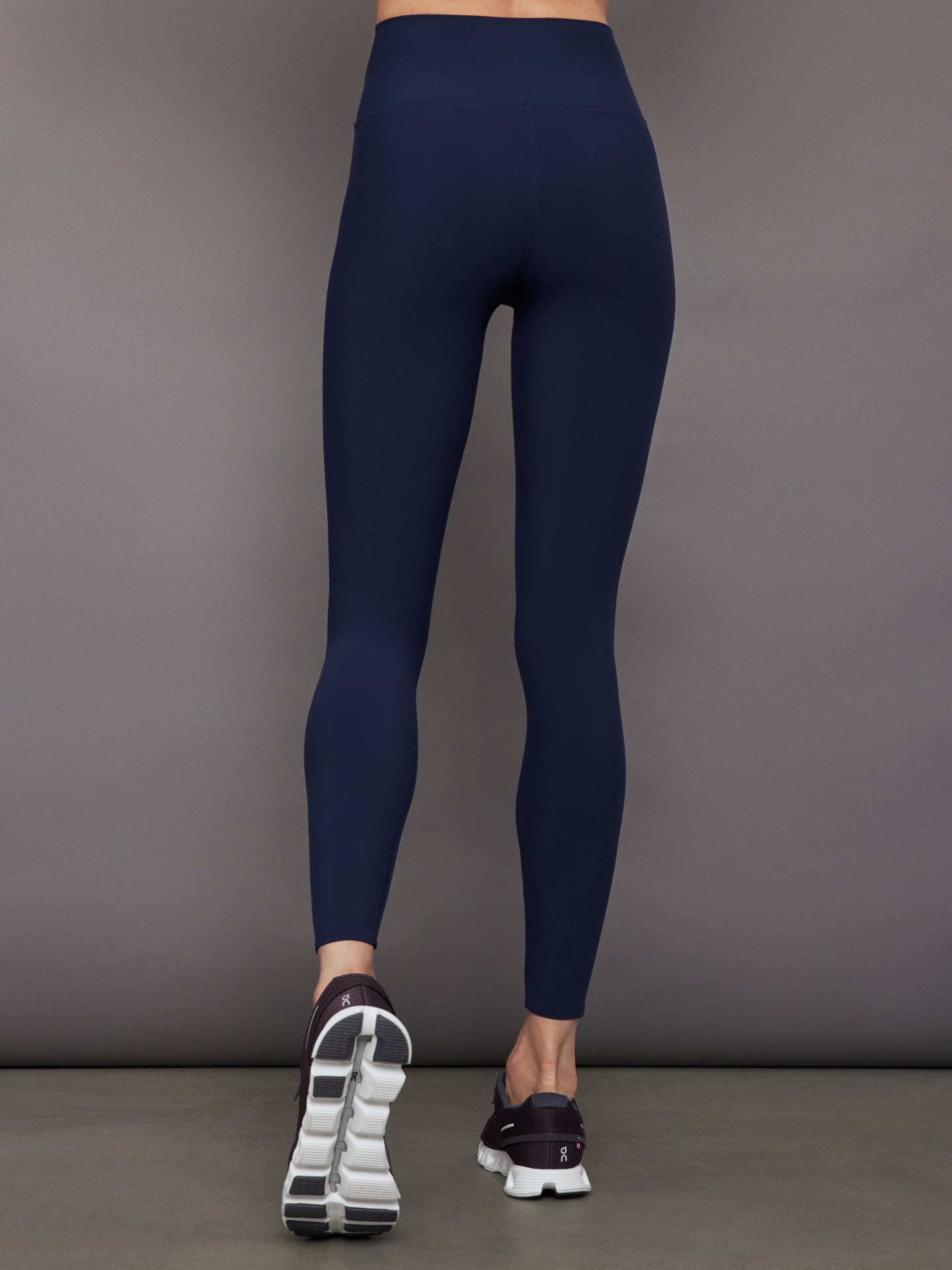 Model wears navy high-rise, full-length leggings with a matte finish and a smooth, body-hugging fit.
