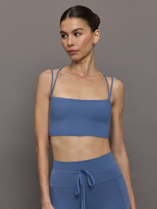 Model wearing Blue Horizon strappy sports bra, front view close-up.
