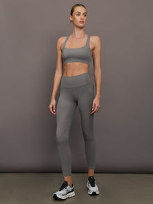 Model wears steel grey-colored racerback bra with a ribbed texture, square neckline, and wide straps that merge at the back.
