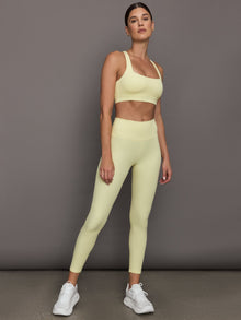 Model wears a buttery soft, ribbed pastel yellow square neck bra with a racerback silhouette. 