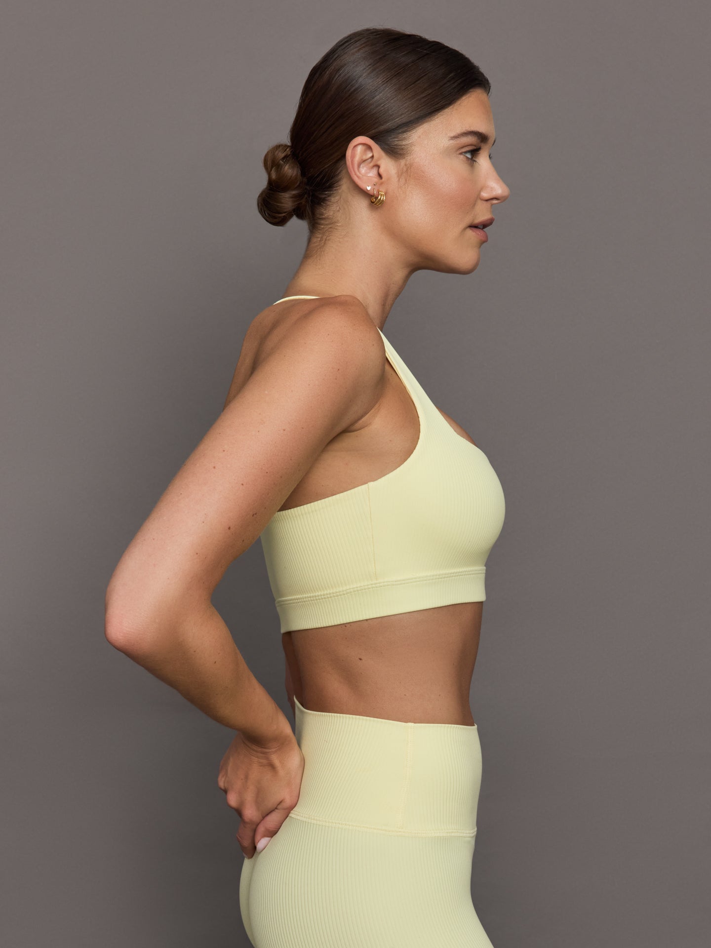 Model wears a buttery soft, ribbed pastel yellow square neck bra with a racerback silhouette. 