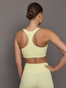 Model wears a buttery soft, ribbed pastel yellow square neck bra with a racerback silhouette. 