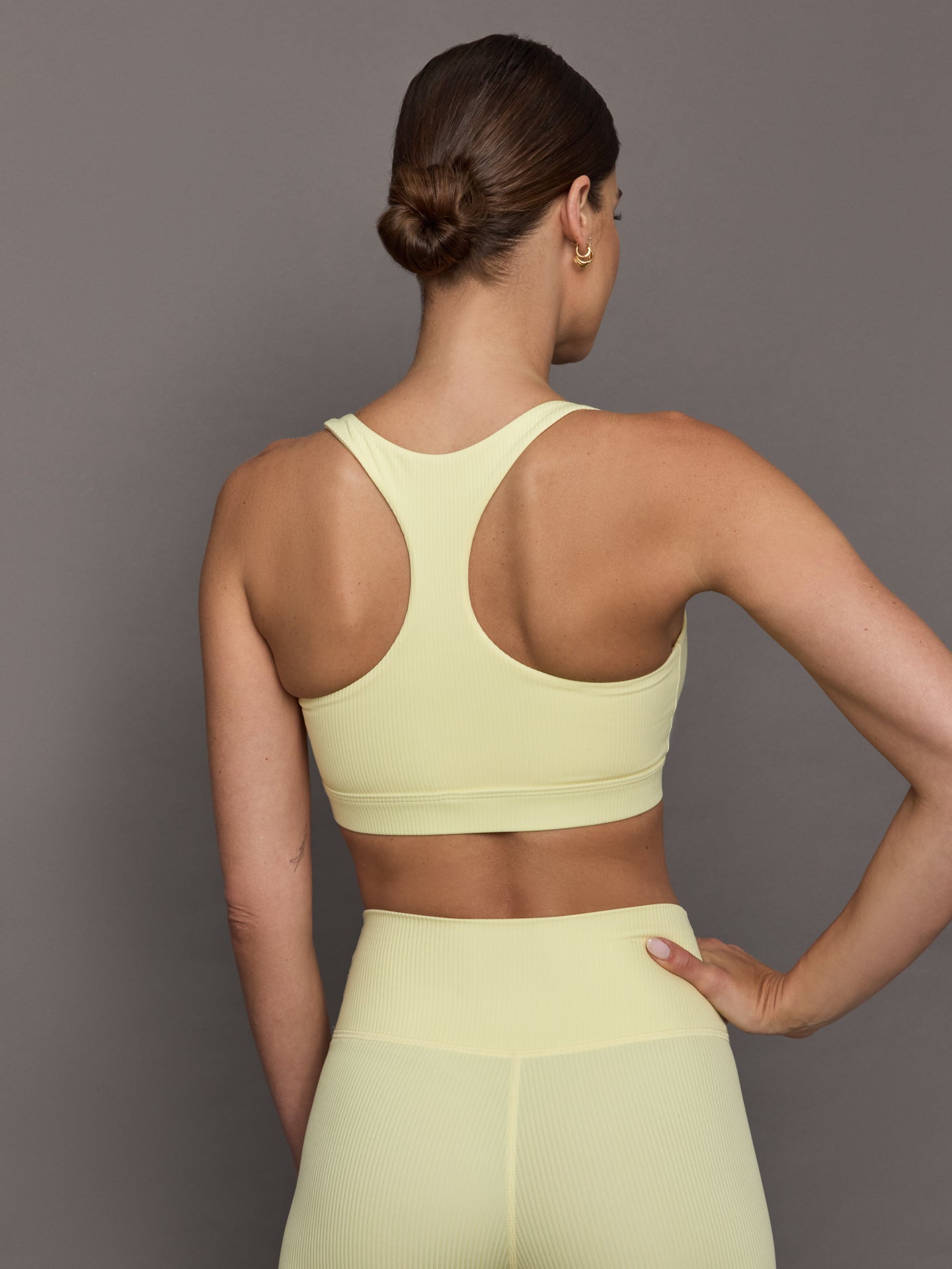 Model wears a buttery soft, ribbed pastel yellow square neck bra with a racerback silhouette. 