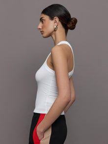 Model wears a white high neck ribbed jersey tank. 