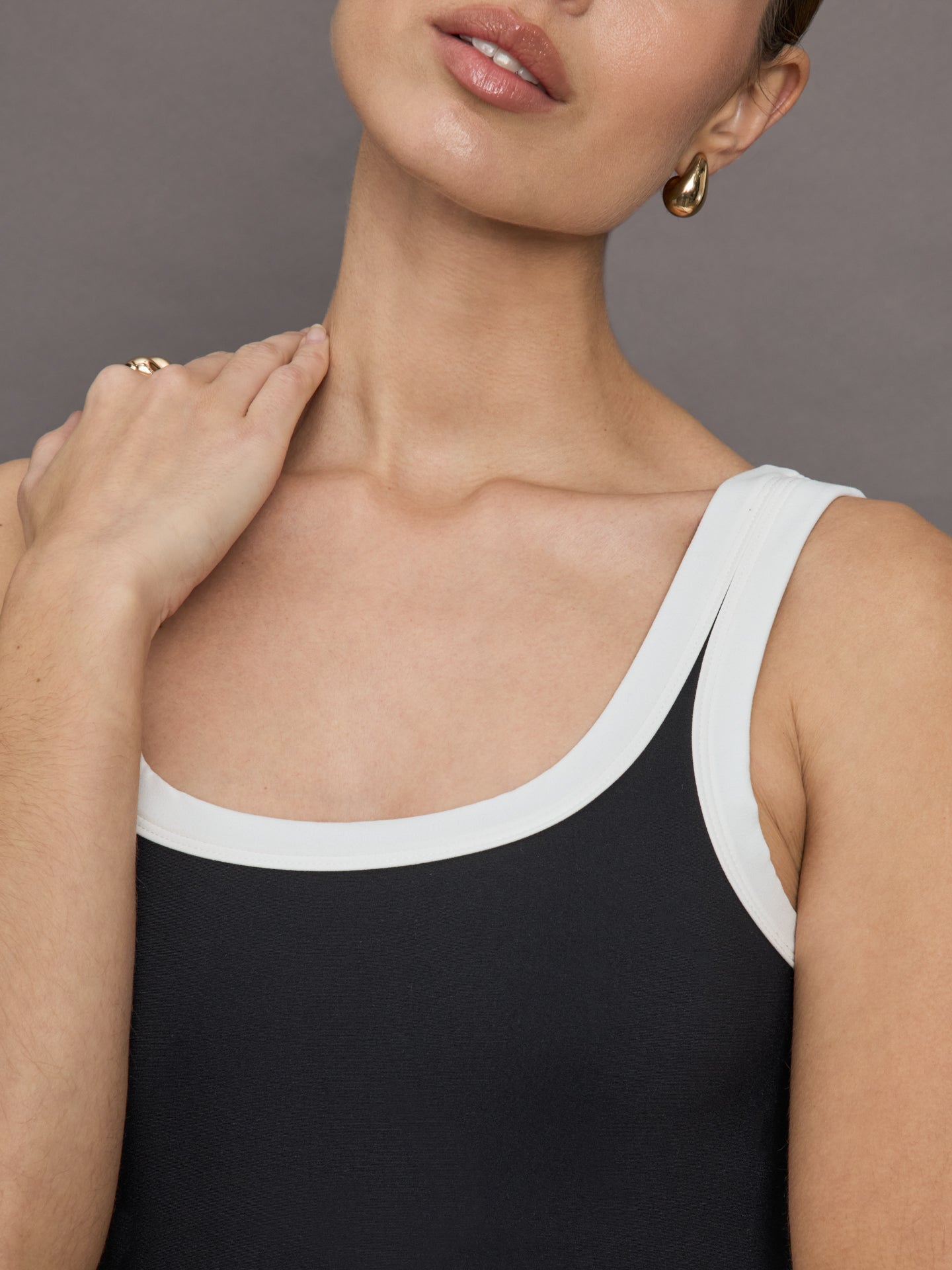 Model wears a black tank top with thick white straps and a scoop tank neckline.