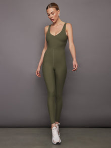 Model wearing olive green v-neck jumpsuit with plunging neckline, front view.