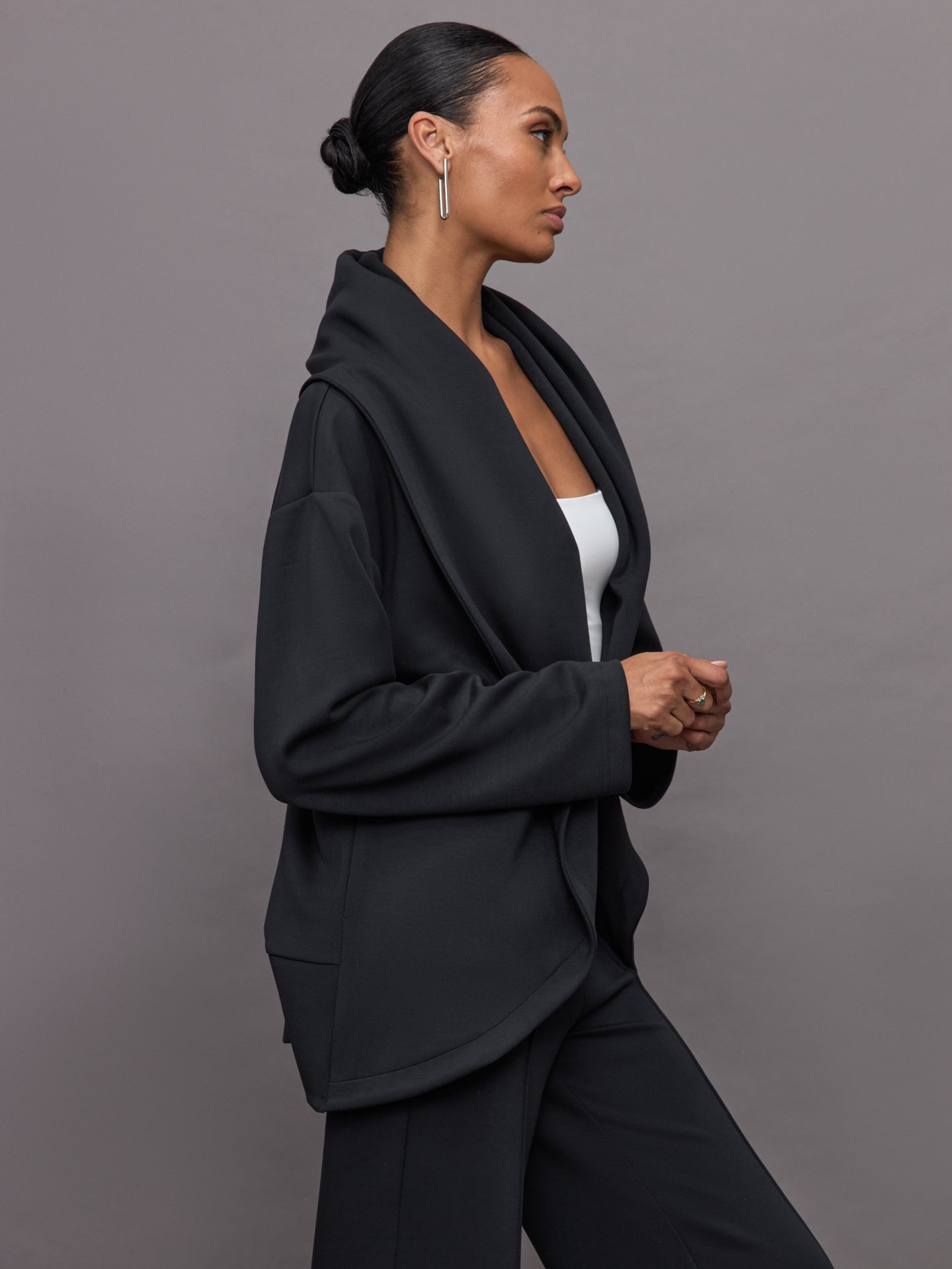 Model wears black open-front cardigan with a loose, draped fit, wide bell sleeves, and side pockets.