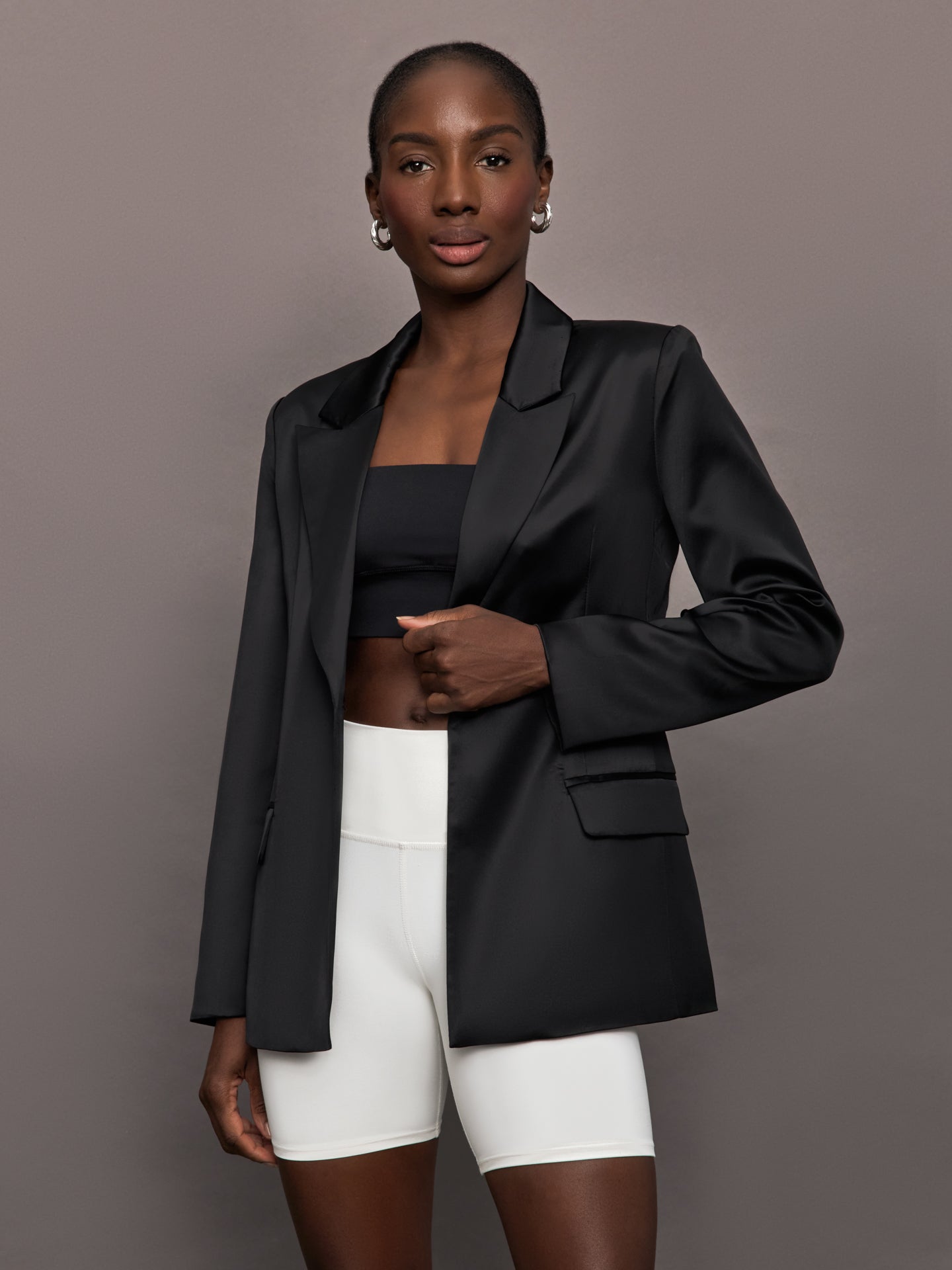 Model wears a black satin single breasted blazer. 