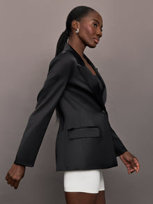 Model wears a black satin single breasted blazer. 