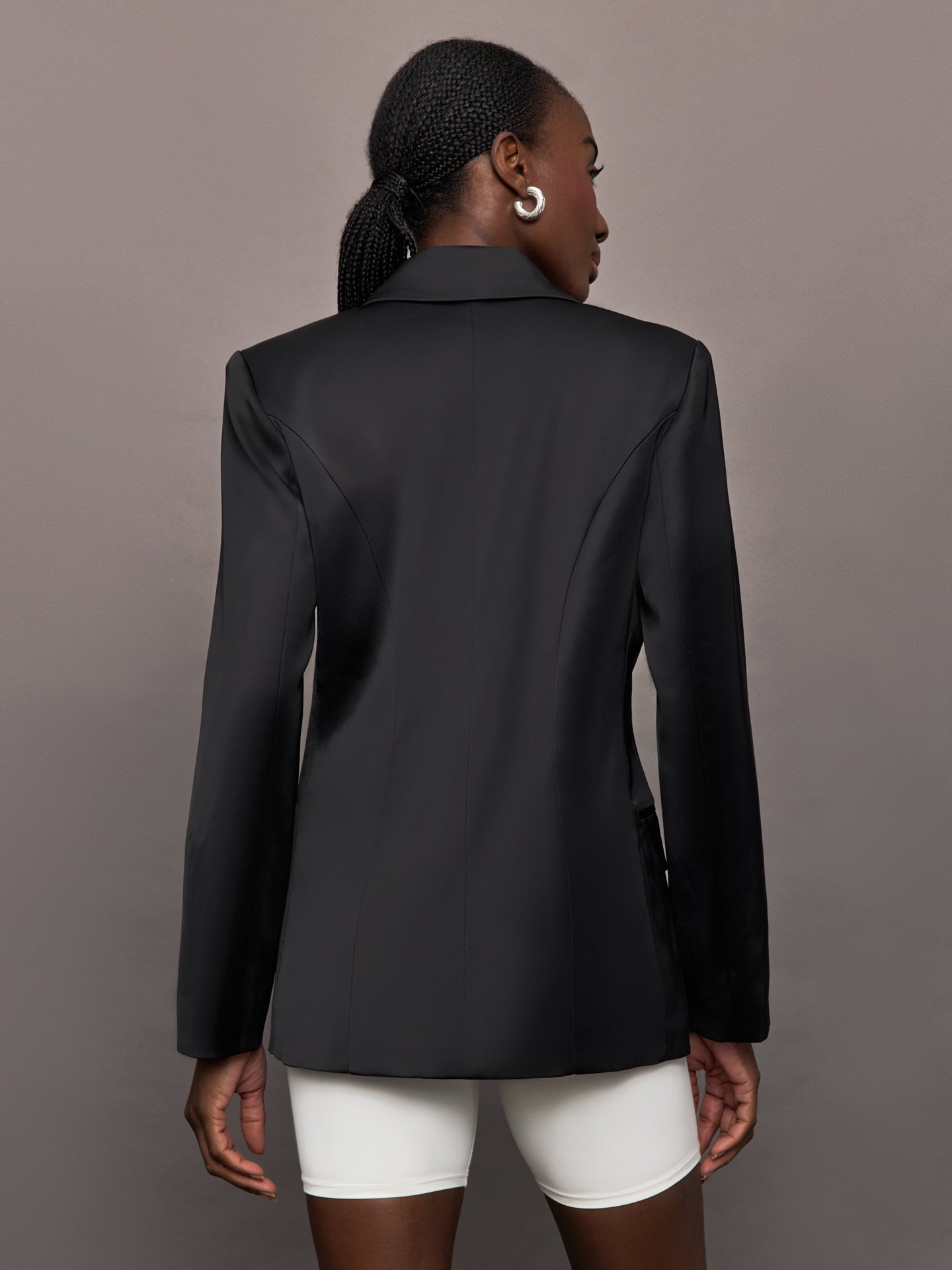 Model wears a black satin single breasted blazer. 