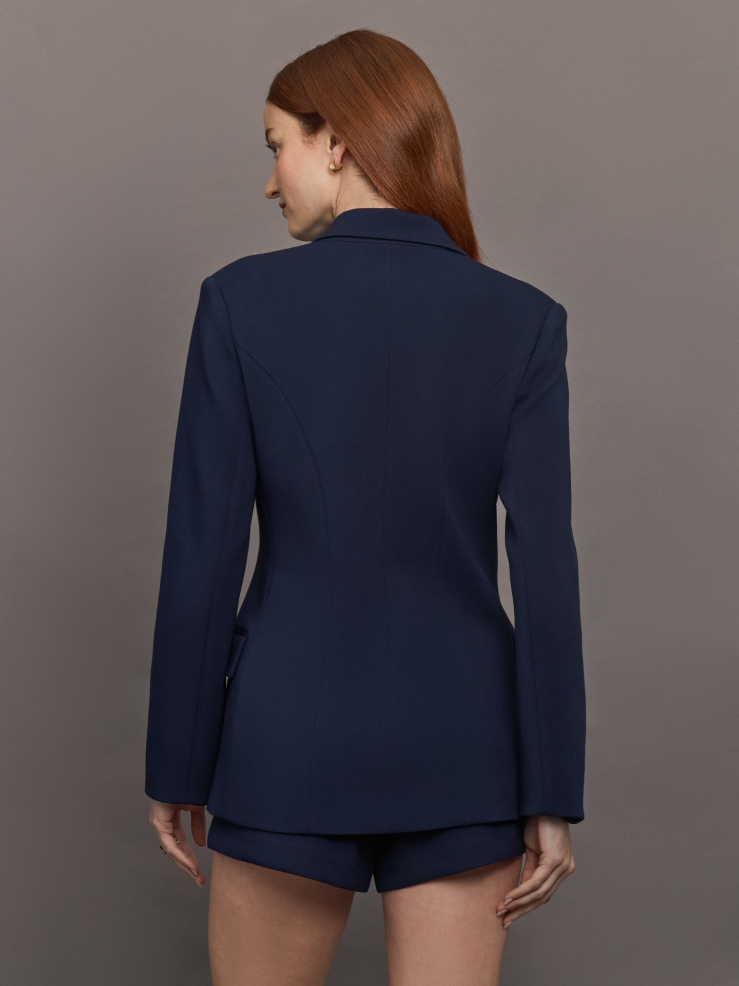 Model wears the Navy double-breasted blazer in Scuba, with a tailored fit, and a smooth, contoured finish.