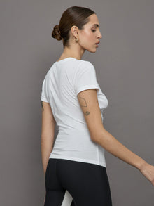 Model wears white short sleeve T-shirt with ruching down the center of the chest until the belly button. 