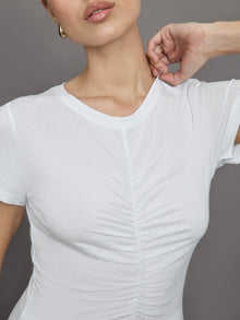 Model wears white short sleeve T-shirt with ruching down the center of the chest until the belly button. 