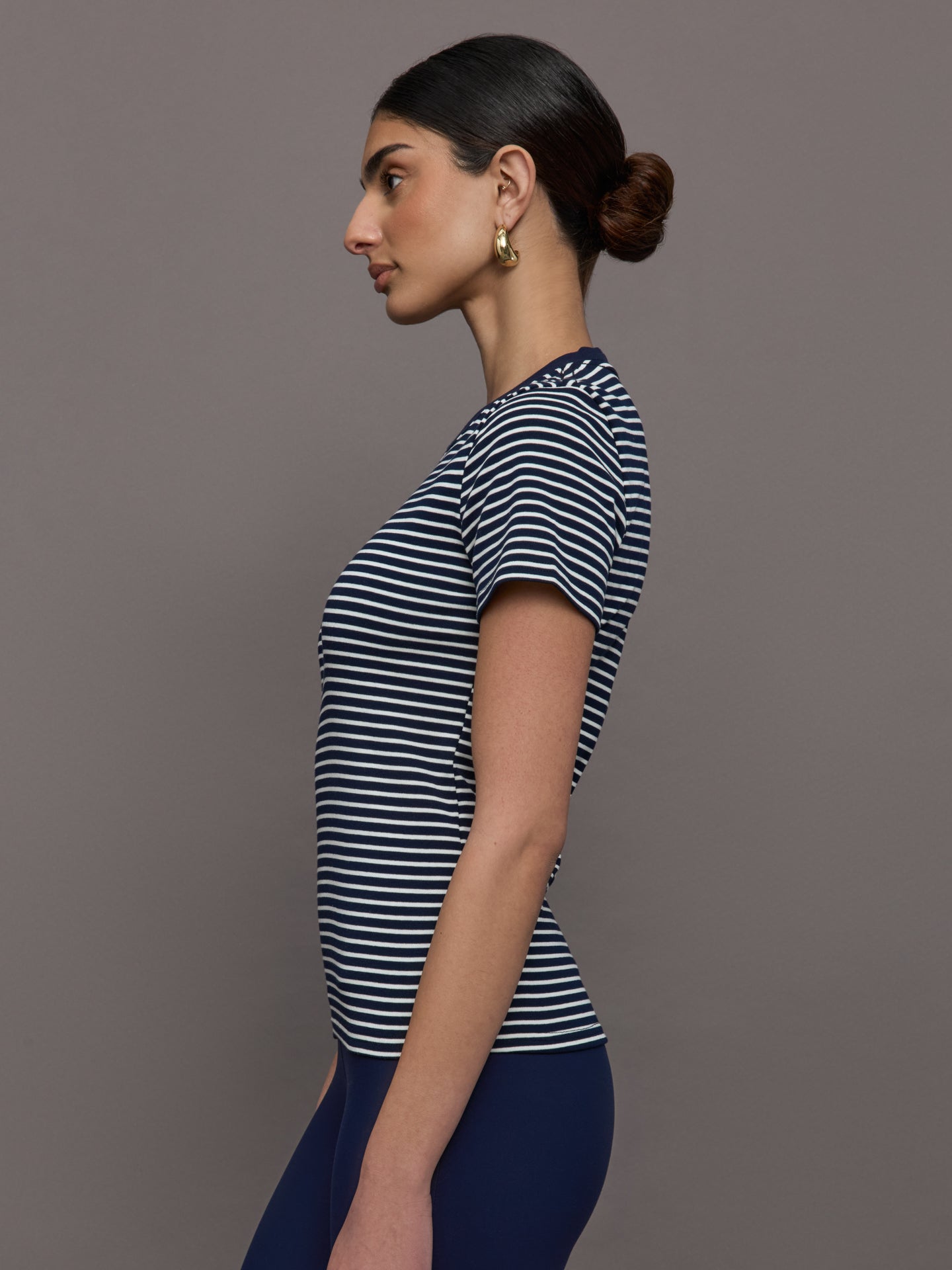 Model wears a navy and white horizontal striped short sleeve ringer tee. 