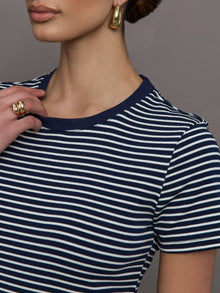 Model wears a navy and white horizontal striped short sleeve ringer tee. 