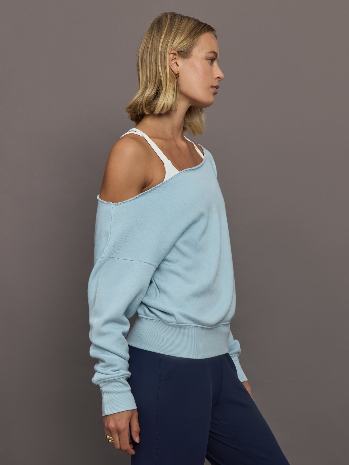 Model wears a light blue off shoulder french terry sweatshirt. 