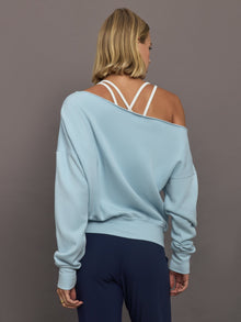 Model wears a light blue off shoulder french terry sweatshirt. 