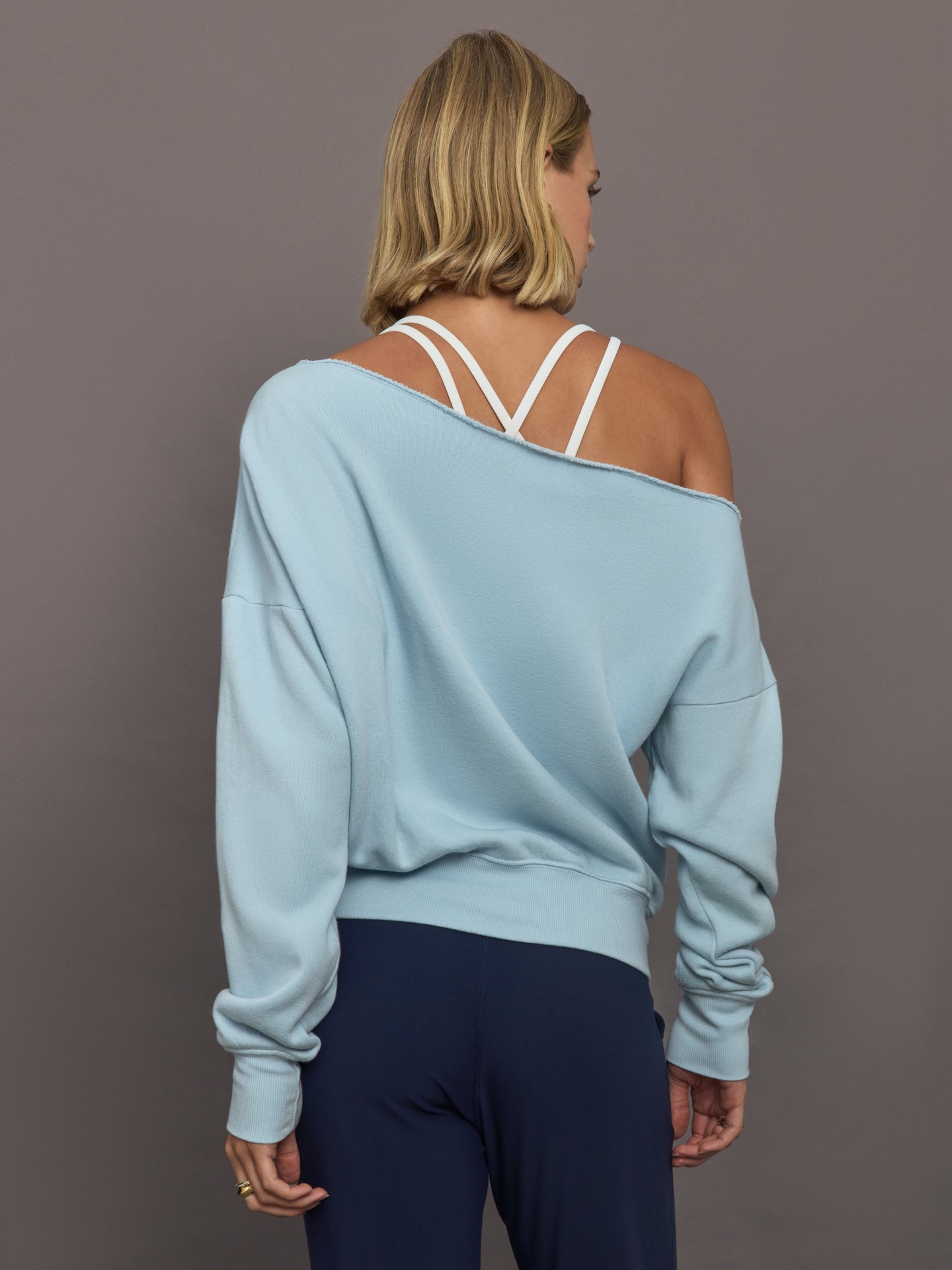 Model wears a light blue off shoulder french terry sweatshirt. 