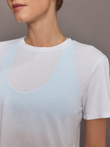 Model wears a cropped boxy white sheer tee shirt. 