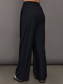 Model wears a pair of black wide leg versatile trousers. 