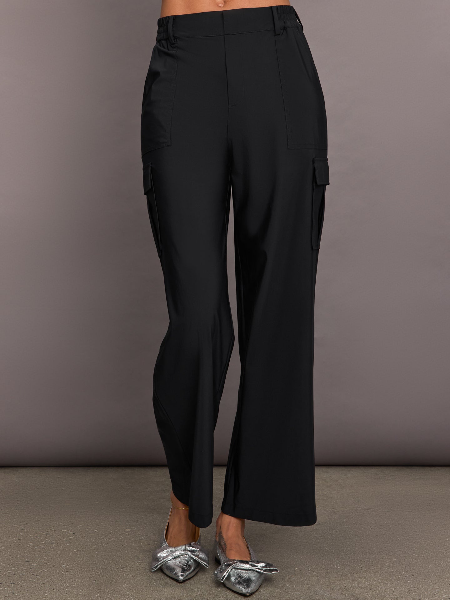 A pair of black stretch woven wide-leg cargo pants with oversized pockets, displayed on a model without showing the upper part of the body.