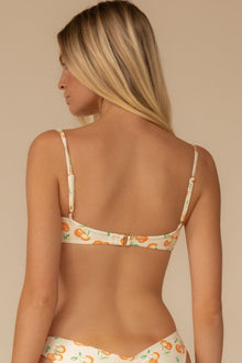 Cream bikini top with orange and green cherry print and adjustable spaghetti straps, shown from back view.