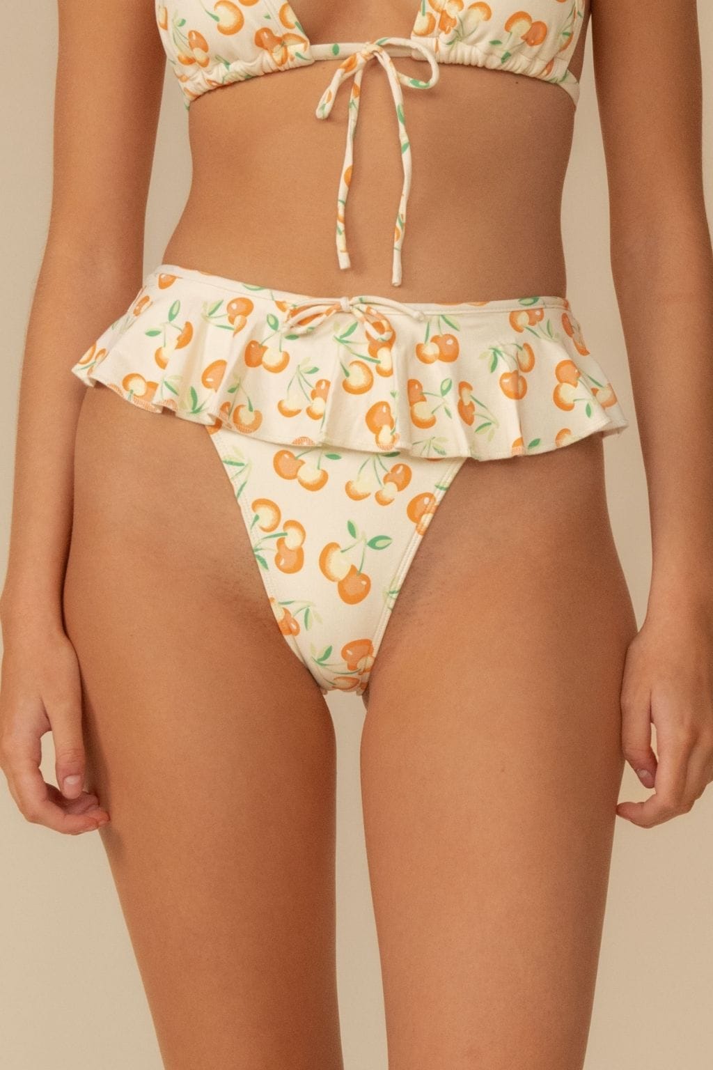 Cream bikini bottom with orange cherry print and ruffled waistband detail.